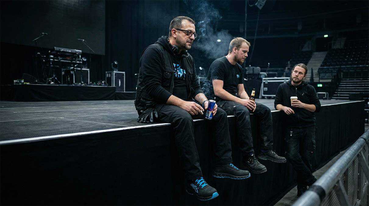 Evenemententechnicus Goran Stojkovic in professionele werkkleding - zwart functioneel poloshirt voor podiumtechniek