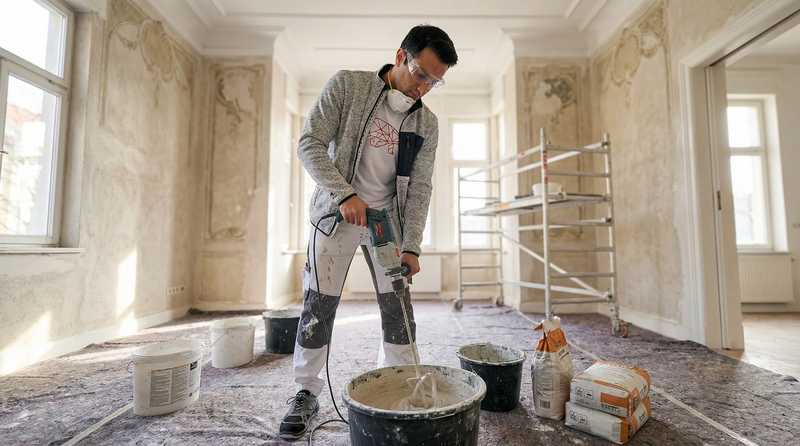 Aras Kaplan mischt Moertel mit Bohrmaschine auf einer Altbau-Baustelle