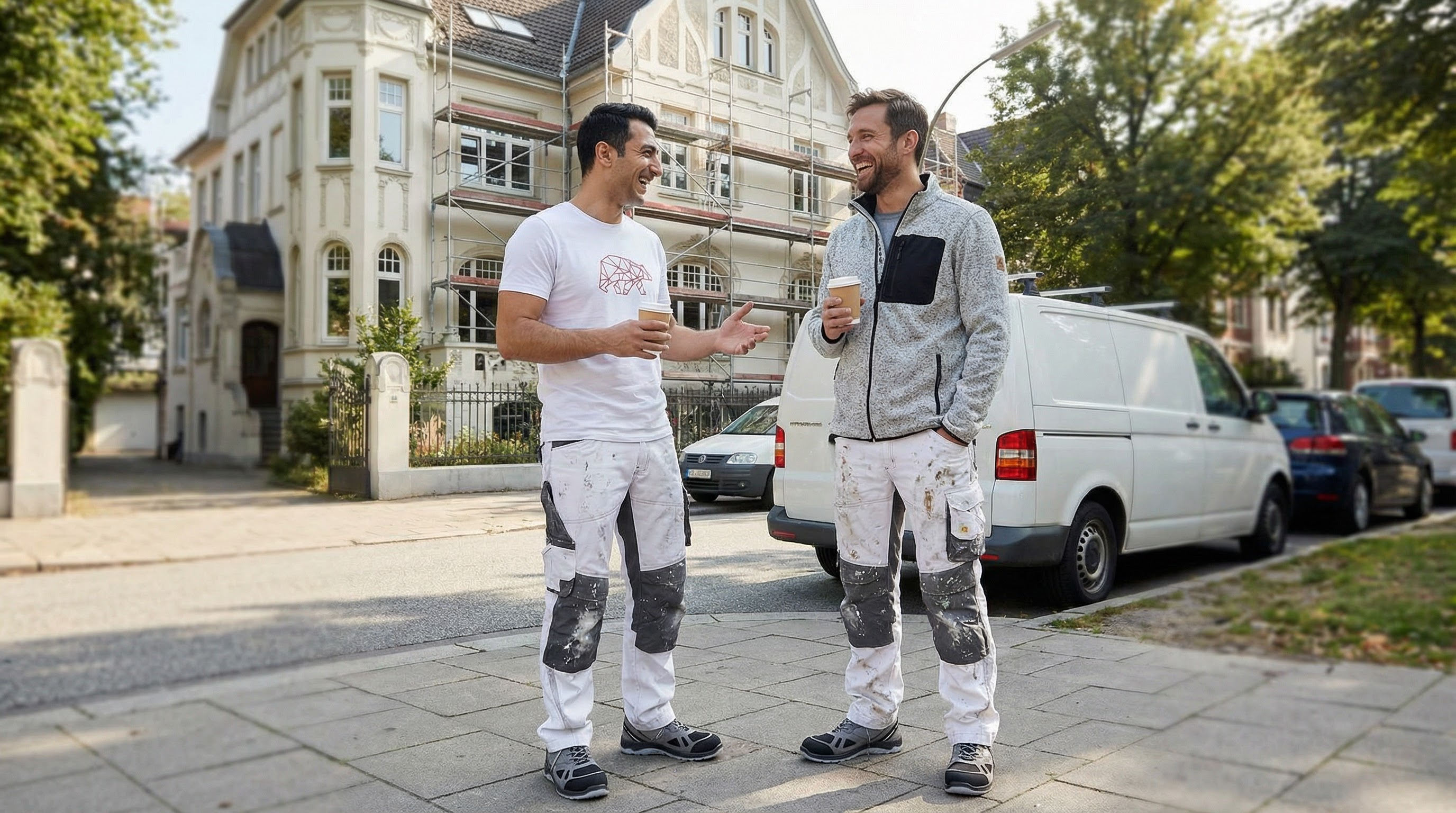 Zwei Stuckateure im Gespraech mit Kaffee auf der Strasse - Kollegialitaet im Handwerk
